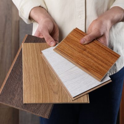 Man with different samples of wooden flooring indoors, closeup