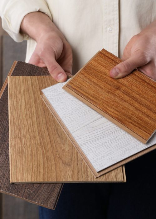 Man with different samples of wooden flooring indoors, closeup
