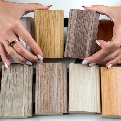 Samples of wood laminate flooring for furniture design and male hands choosing a model at an office desk. A color guide showing the range of shades for use in interior design and decoration designers.